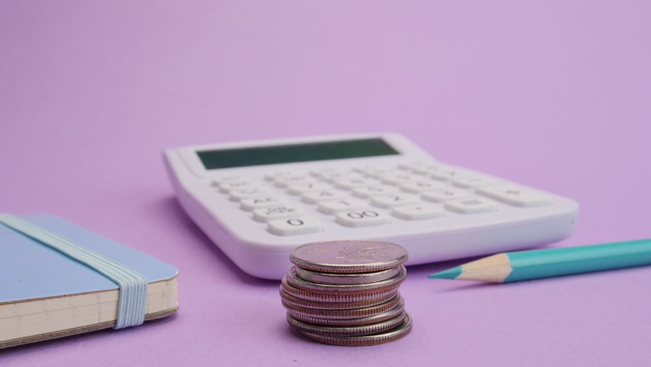 services-02 Calculator, coins, and stationery symbolize budgeting and finance on a pastel purple backdrop.