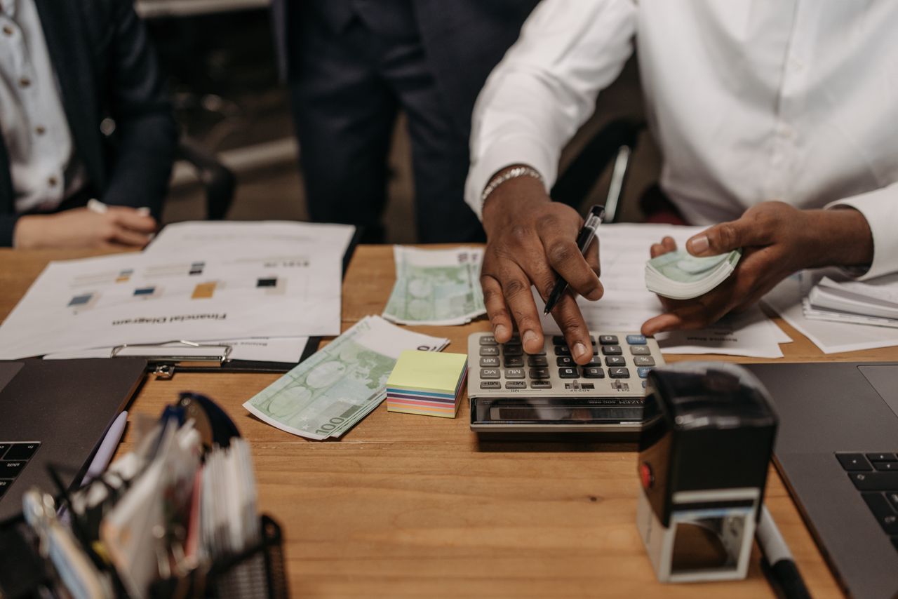why-choose-us Professional setting with people handling cash and calculations using a calculator at a desk.